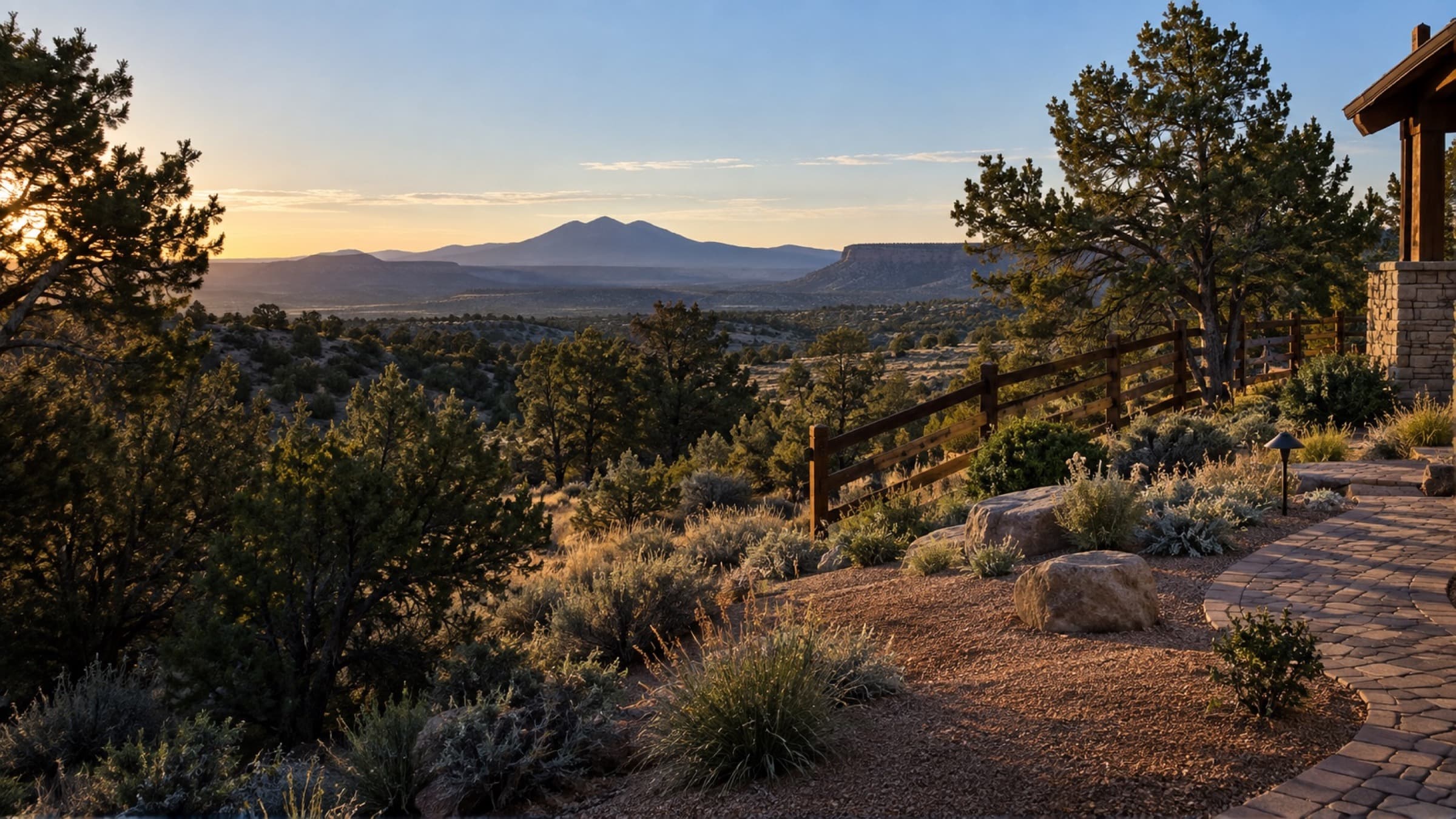 High desert Northern Arizona landscape with juniper, natural stone, a wood fence, and a paver path